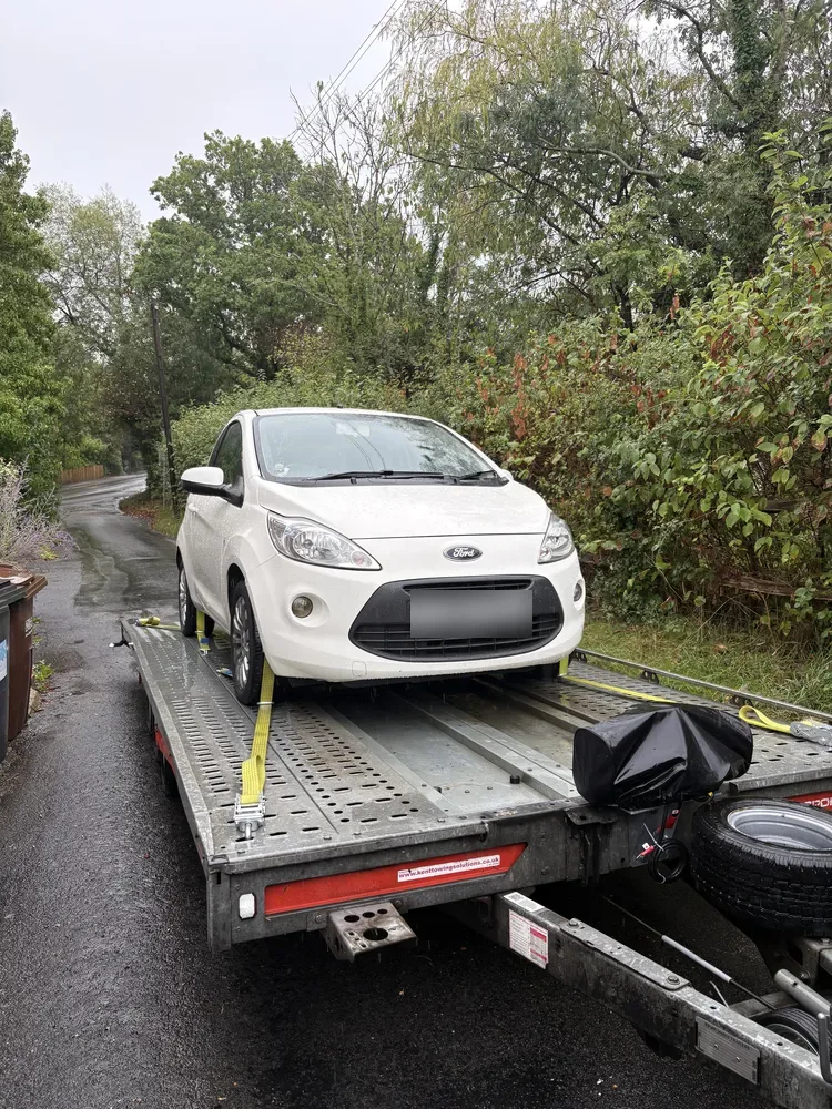 White Ford Ka strapped to the Timeless Transport trailer in a wet Sussex lane