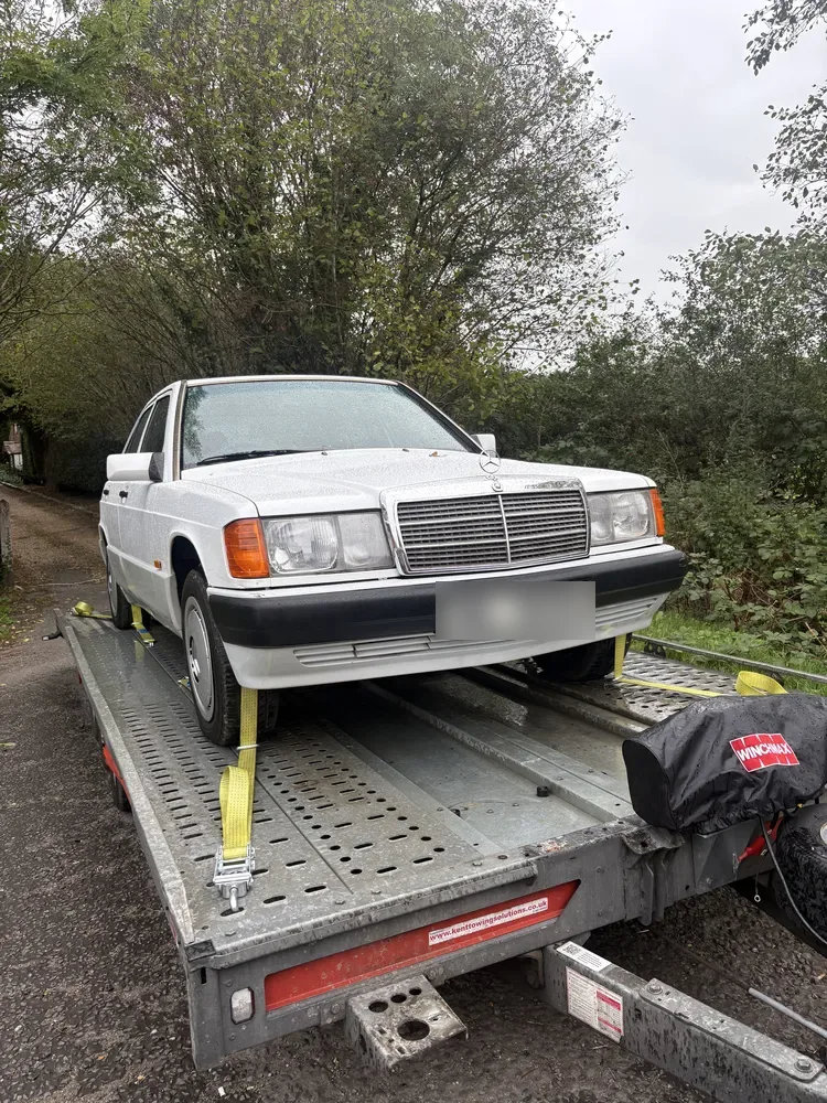 White Mercedes 190 classic on the open trailer