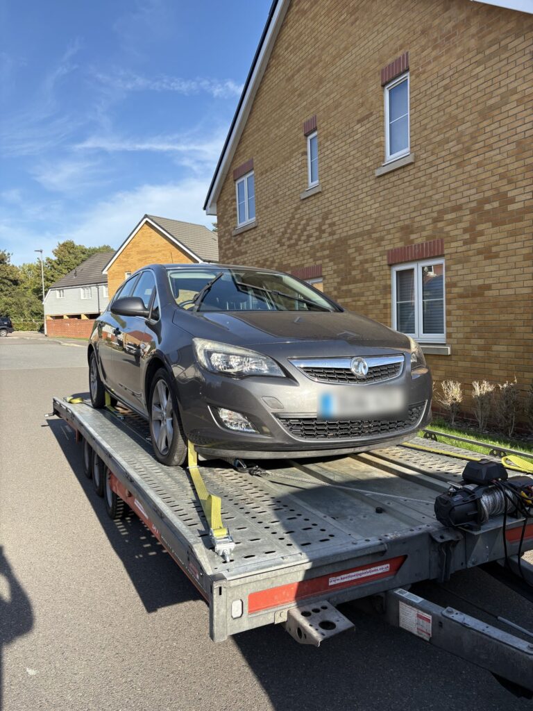 Grey Vauxhall Astra strapped onto the Timeless Transport open trailer during a recovery