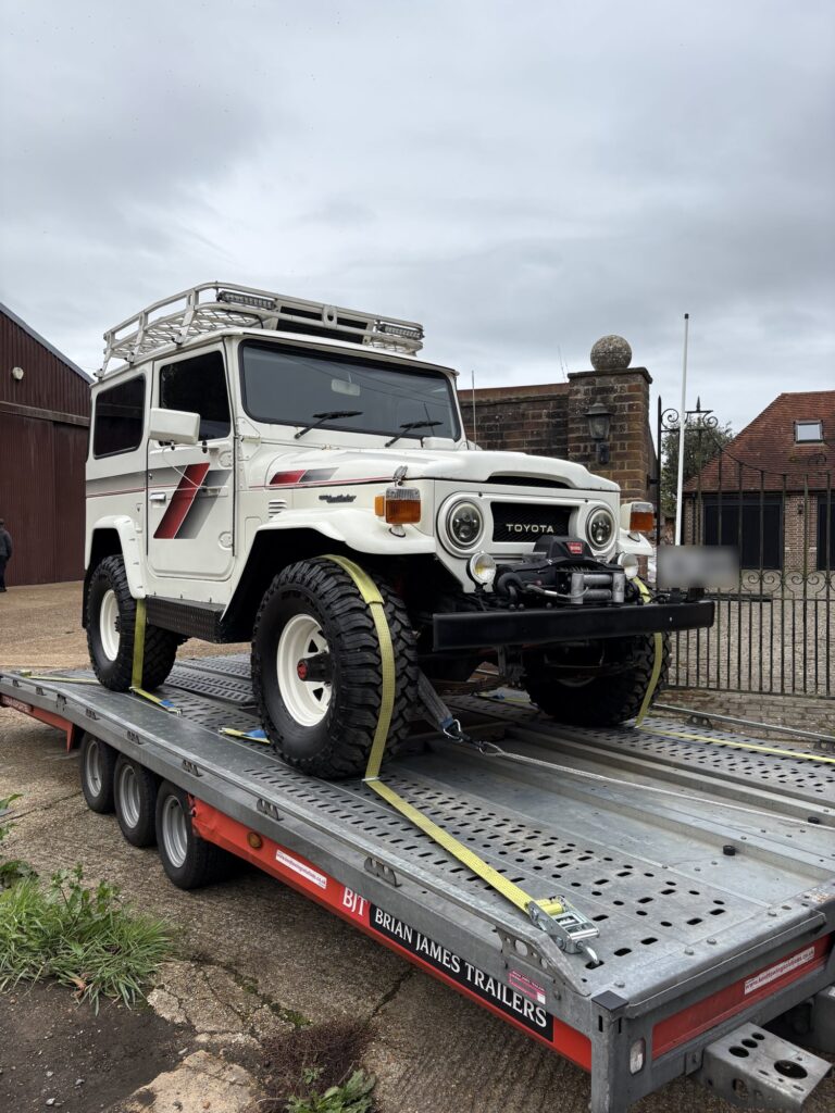 White classic Toyota Land Cruiser strapped down on the Timeless Transport open trailer
