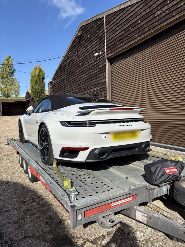 White Porsche 911 Turbo S cabriolet strapped onto the Timeless Transport trailer, seen from the rear